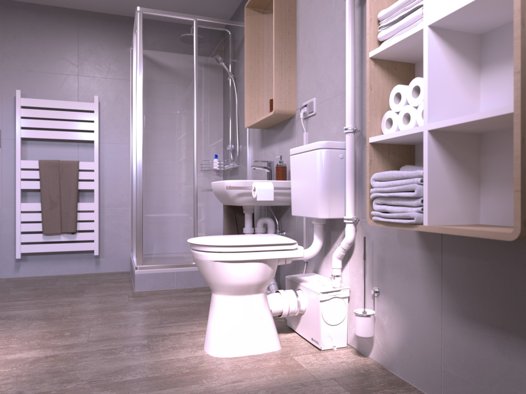 Gros plan sur des toilettes, derrière lesquelles se trouve un petit poste de relevage à lequel est également raccordée une douche.