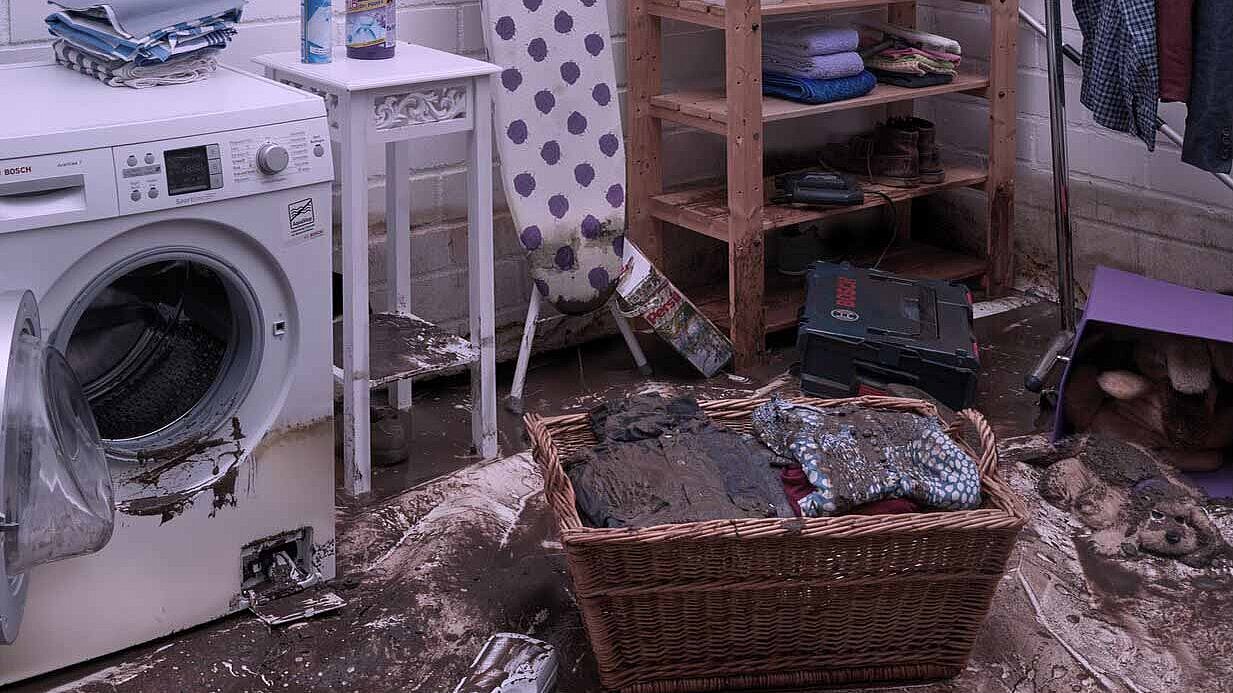 Dégâts dans la buanderie Buanderie avec un panier à linge sale et une machine à laver.